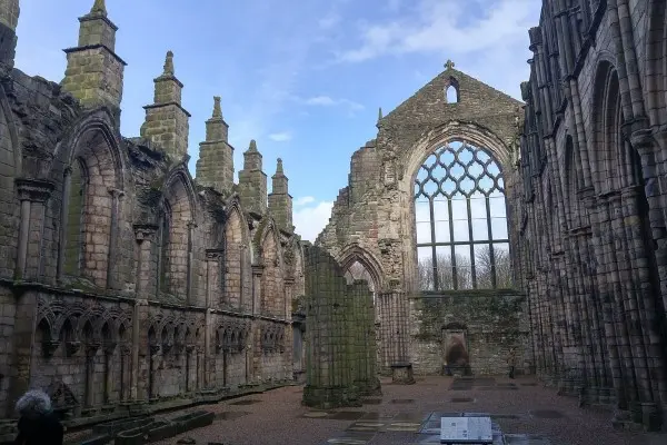 Panoramic view of the Gothic ruins of Holyrood Abbey on a cloudy day, emphasizing its historical grandeur.